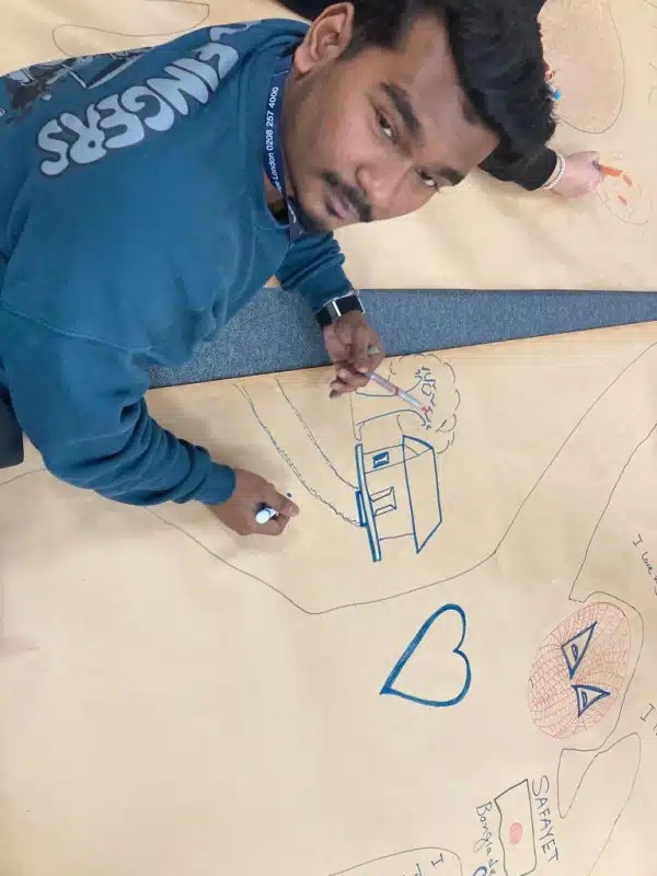 Bridging the gap between them and us 1 Young man looking up from drawing a house