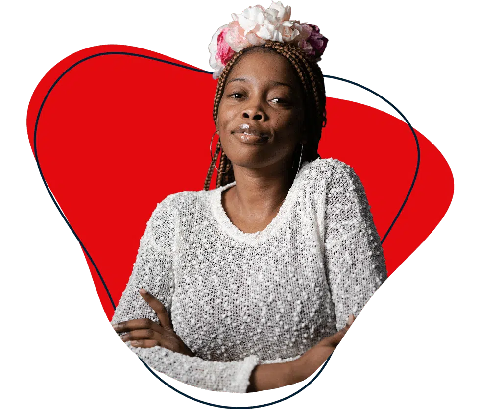A woman with plaited hair and a floral headband wearing a textured white jumper sits with her arms crossed, smiling slightly. The background features an abstract red shape.