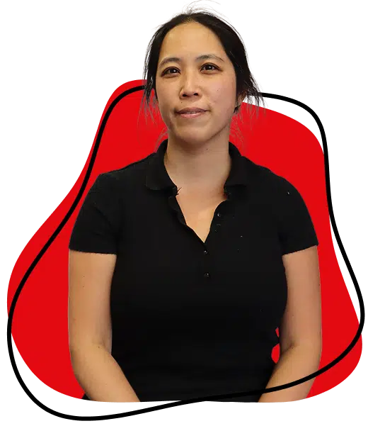 A woman with long dark hair tied back, wearing a short-sleeved black shirt, sits in front of a red abstract background with a black outline.