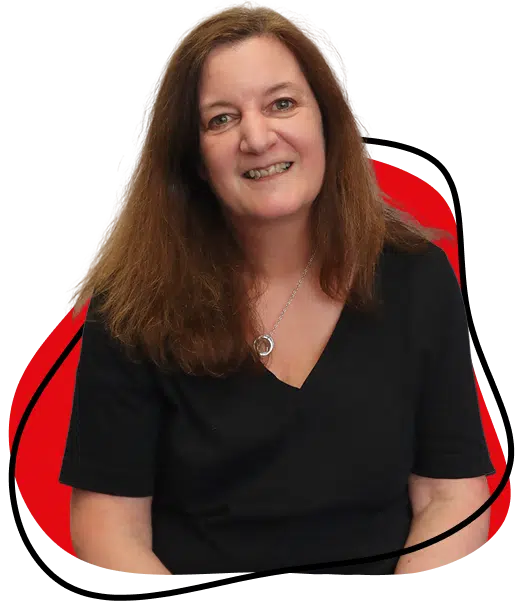 A woman with long brown hair wearing a black top and silver pendant necklace sits in front of a white background with a red, abstract shape behind her, smiling at the camera.