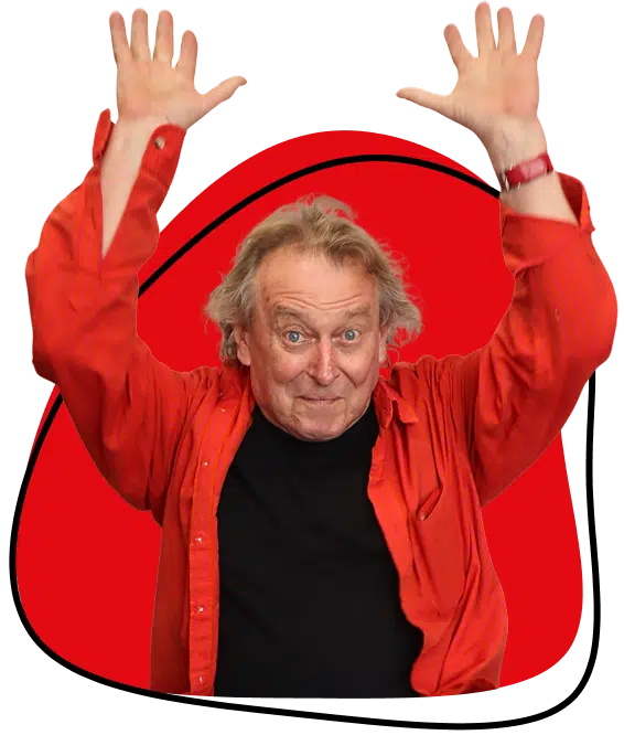 An older man with grey hair, wearing a red shirt over a black shirt, raises both hands enthusiastically. He stands in front of a red, rounded shape with a black outline on a light background.