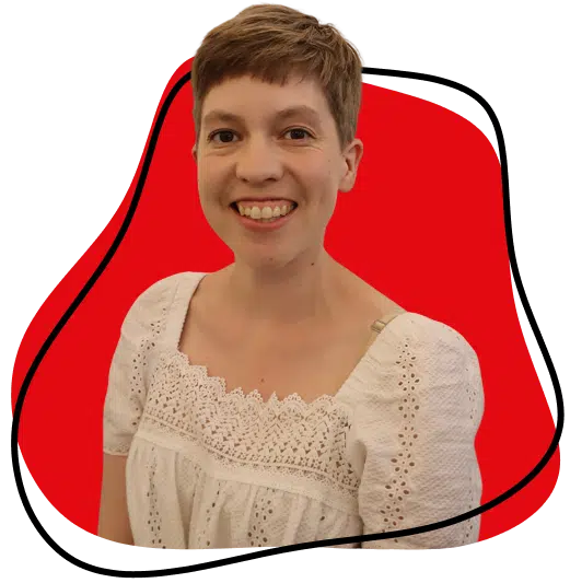 A smiling person with short light brown hair wears a white broderie anglaise blouse. The background features a red shape outlined with a black line.