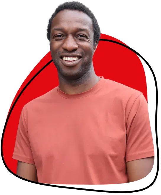A smiling man wearing a salmon-coloured T-shirt stands in front of a white background with a red abstract shape behind him.
