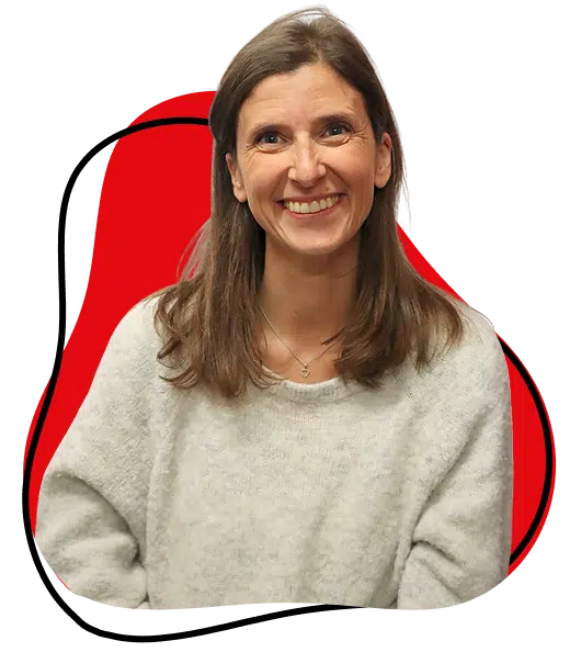 A woman with long brown hair, wearing a light grey jumper, smiles at the camera. She is posed in front of an abstract red and black background shape.