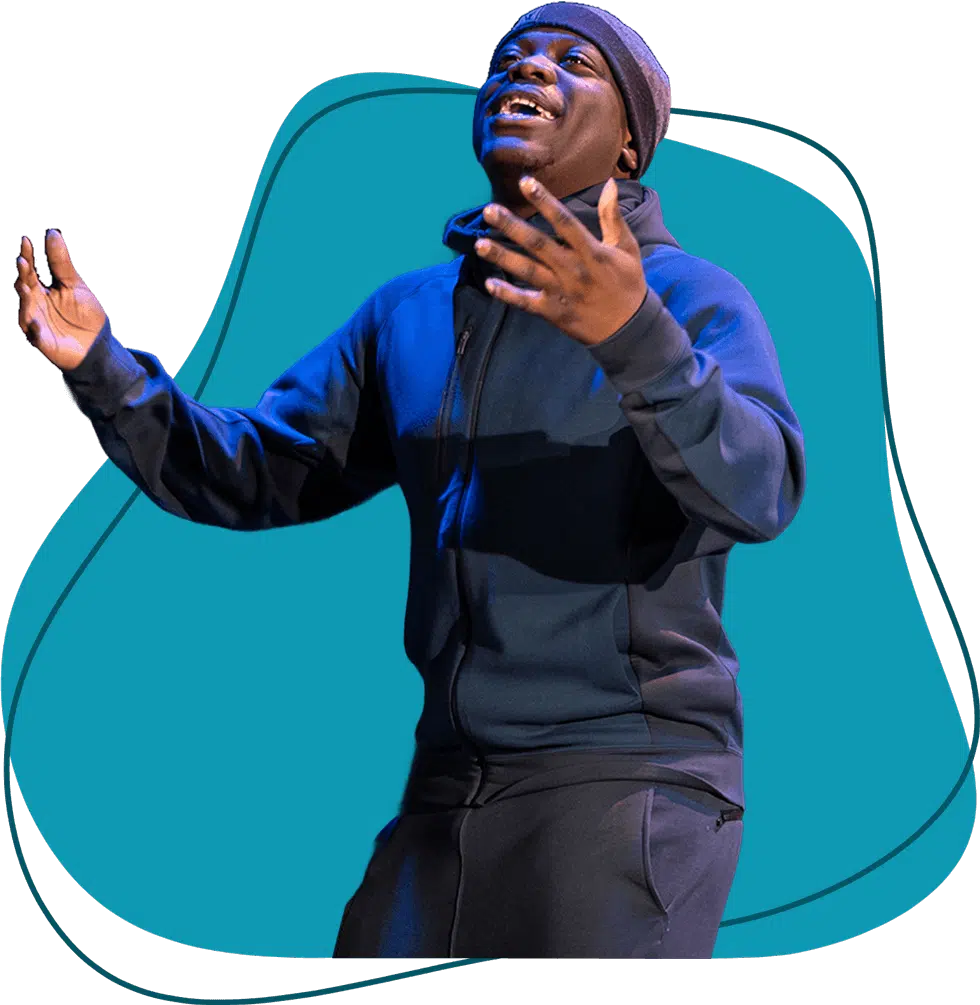 A person wearing a beanie and dark hoodie gestures expressively with both hands, standing in front of a blue abstract background shape.