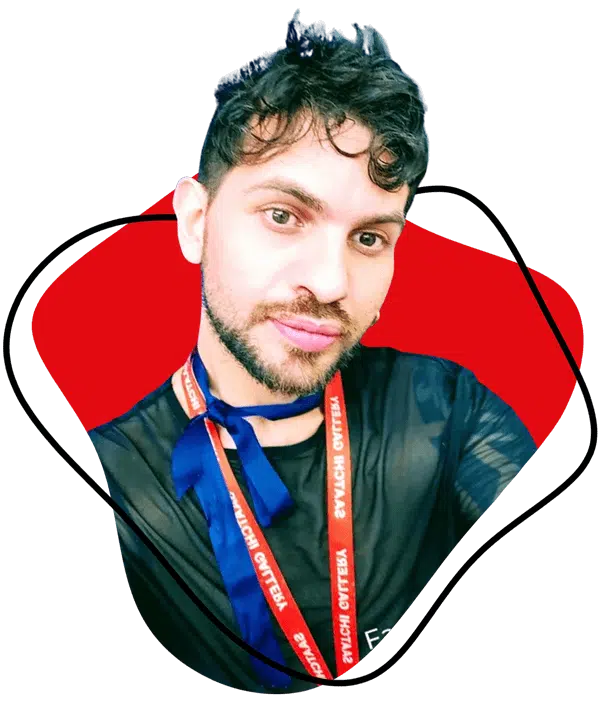 A person with short, curly dark hair and a trimmed beard wears a sheer black top, a blue ribbon round their neck, and a red lanyard. The background features red and black abstract shapes.